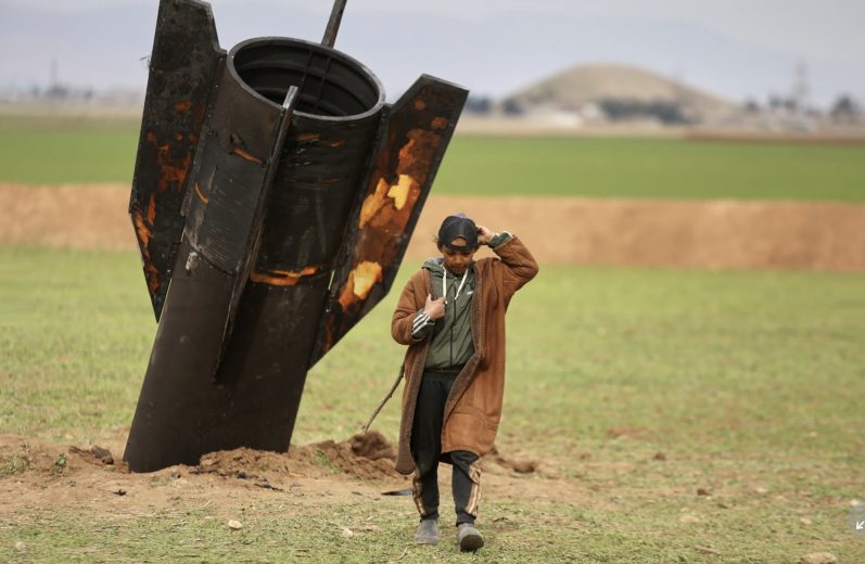 A shepherd boy walks away from an unexploded Iranian projectile